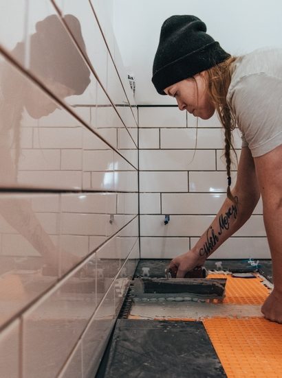 femme qui pose du carrelage dans une salle de bain