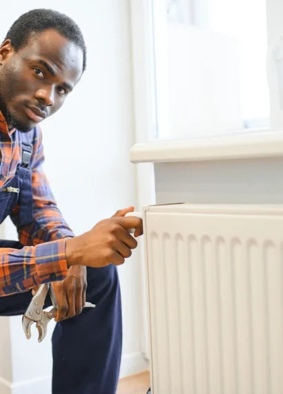 Un homme en combinaison bleu qui regarde un radiateur blanc