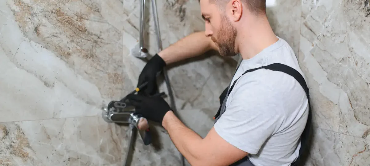 Un plombier qui répare les tuyaux dans la douche