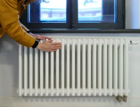 Une personne qui pose la main sur un radiateur en fonte blanc