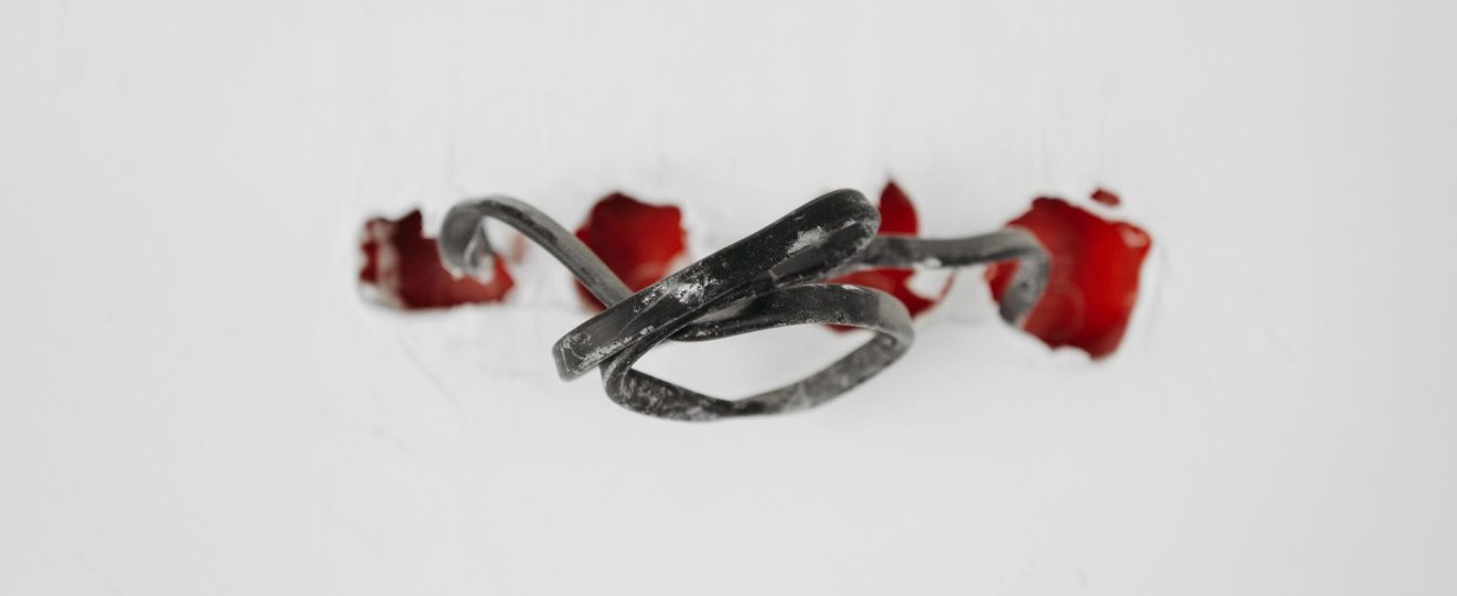 A close-up of a tangled wire protruding from red holes in a white background.