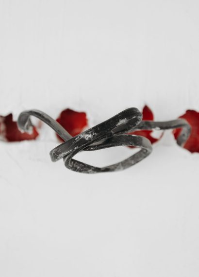 A close-up of a tangled wire protruding from red holes in a white background.