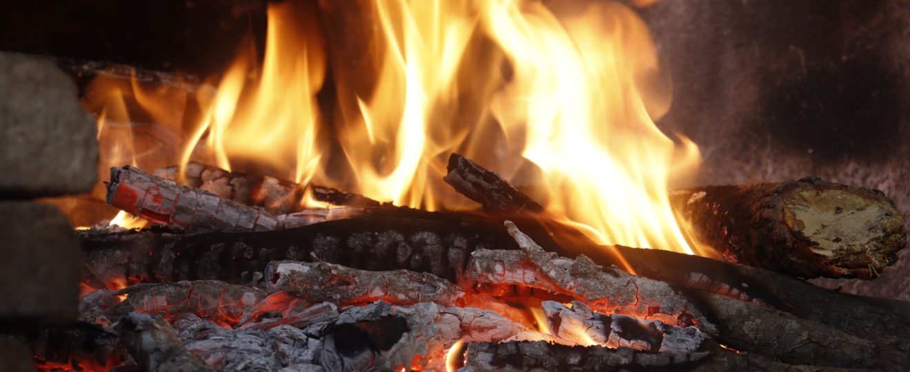 Close-up of a blazing fireplace with logs and glowing embers creating a warm atmosphere.