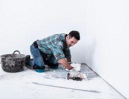 Man kneeling applying white compound to floor
