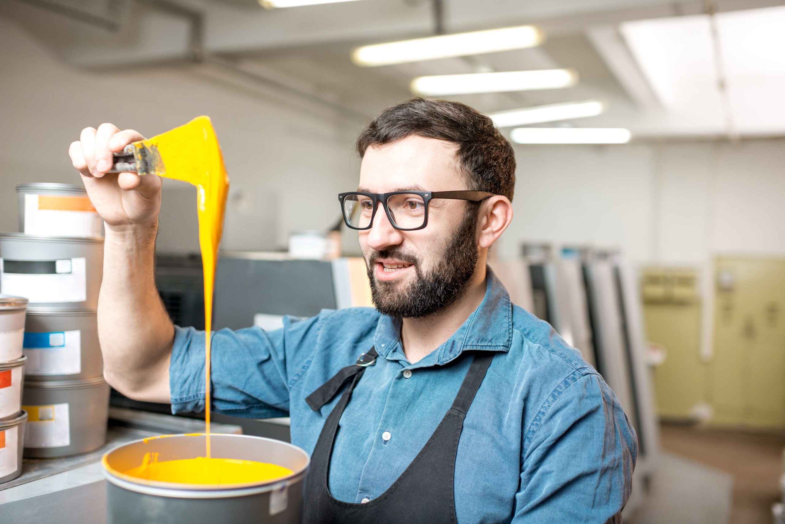 Man mixing vivid yellow paint in workshop