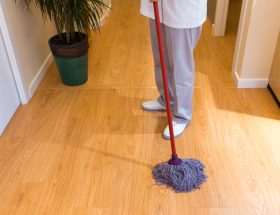 Person mopping the wooden floor indoors