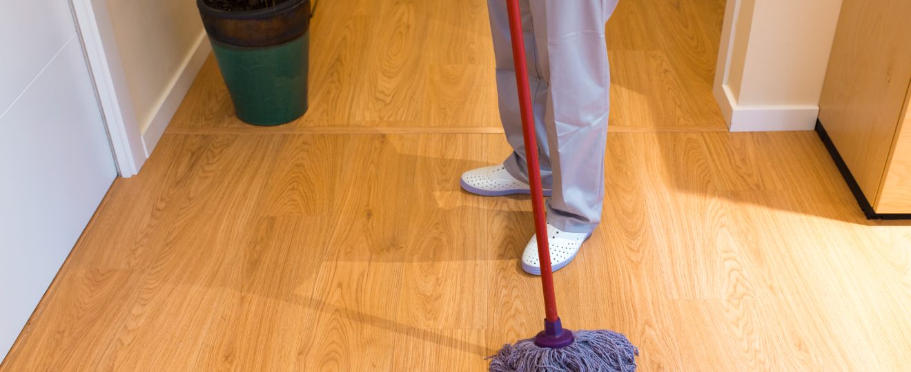 Person mopping the wooden floor indoors