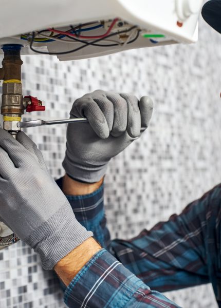 Plumber repairs pipe with wrench in home