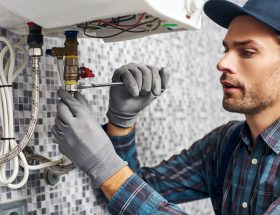 Plumber repairs pipe with wrench in home