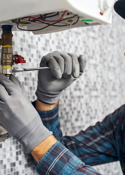 Plumber repairs pipe with wrench in home