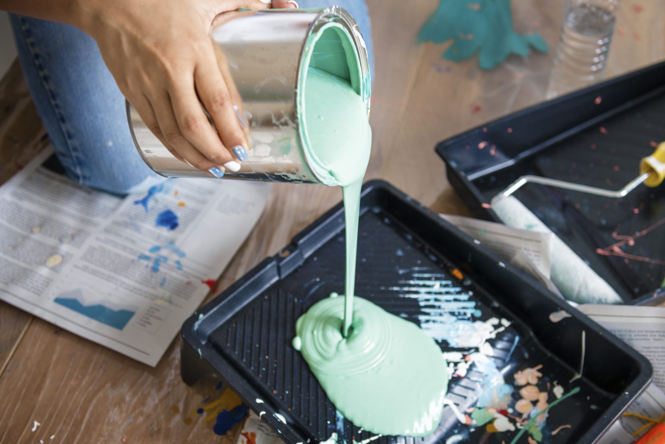 Pouring light blue paint into a tray