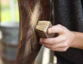 Sanding a wooden chair leg outside