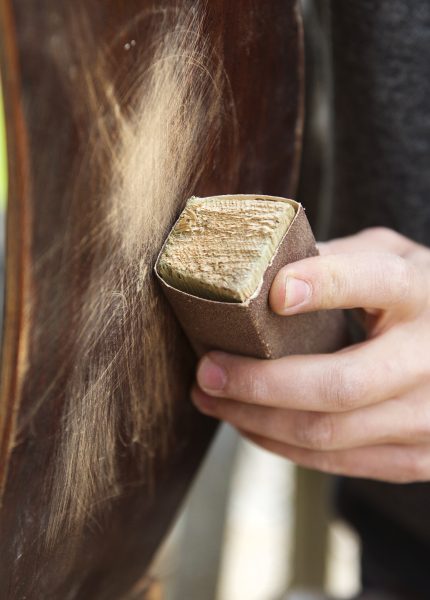Sanding a wooden chair leg outside