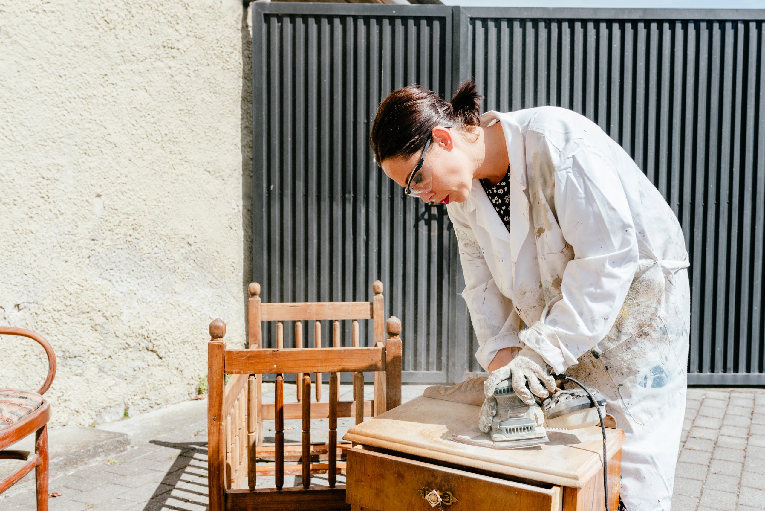 Woman sanding furniture outside on a sunny day